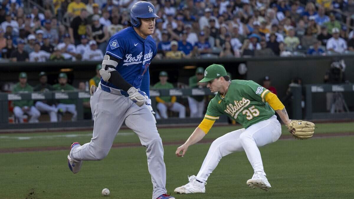 Los Angeles Dodgers two-way player Shohei Ohtani runs to first base as Athletics pitcher J.T. Ginn picks up the ball during a game Wednesday at Sutter Health Park in West Sacramento.