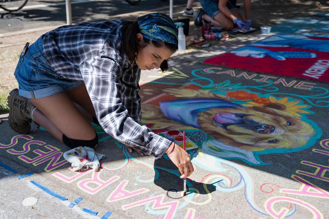 Nadia Garcia uses chalk paint for fine lines on her mural at Chalk It Up on Sunday at Fremont Park.
