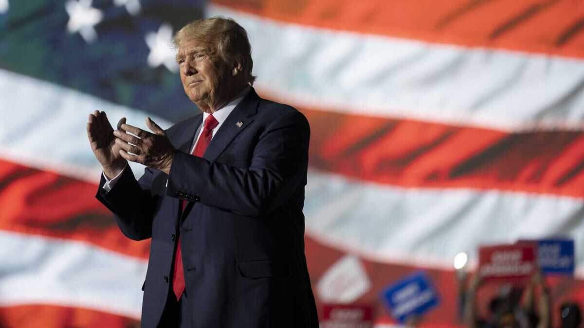 Former President Donald Trump applauds Saturday while attending a rally at the Minden Tahoe Airport in Minden, Nev.