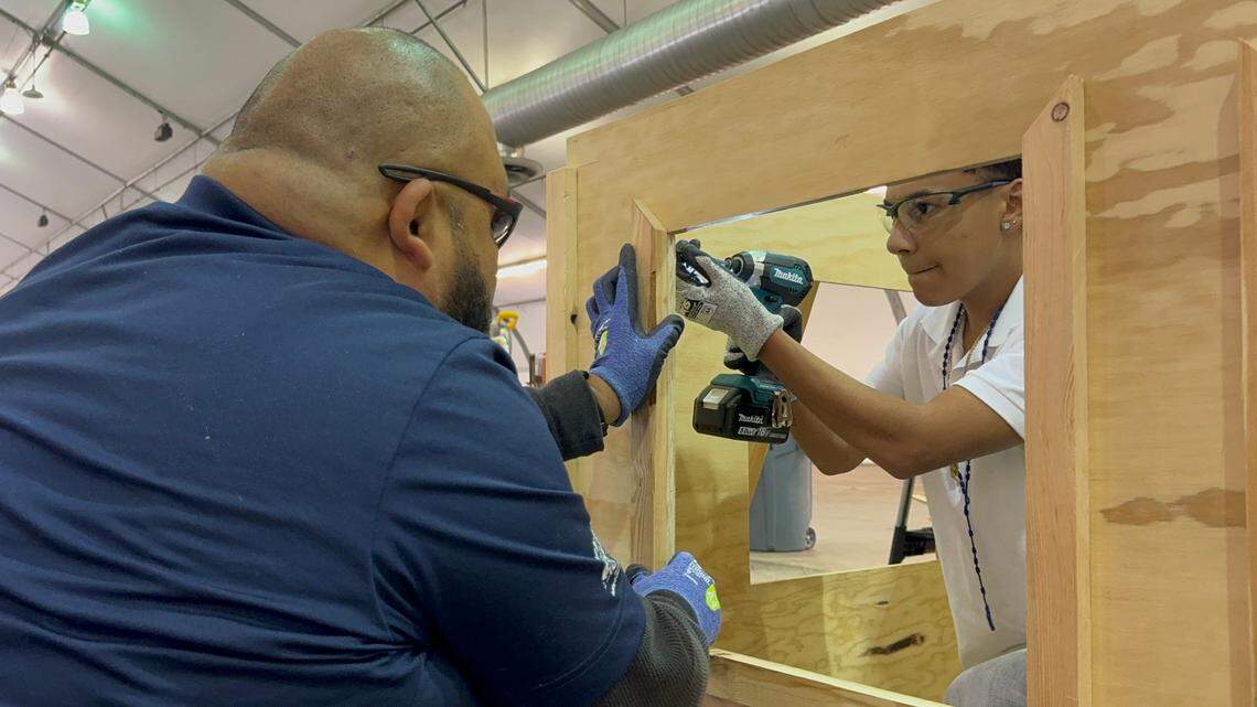 Alexis Araujo, an 11th-grade student at S. William Abel Academy in Williams, learns how to frame a window Wednesday, Oct. 9, 2024 with help from laborer Carlos Gomez, left, during High School Trades Day at Sacramento’s Cal Expo.