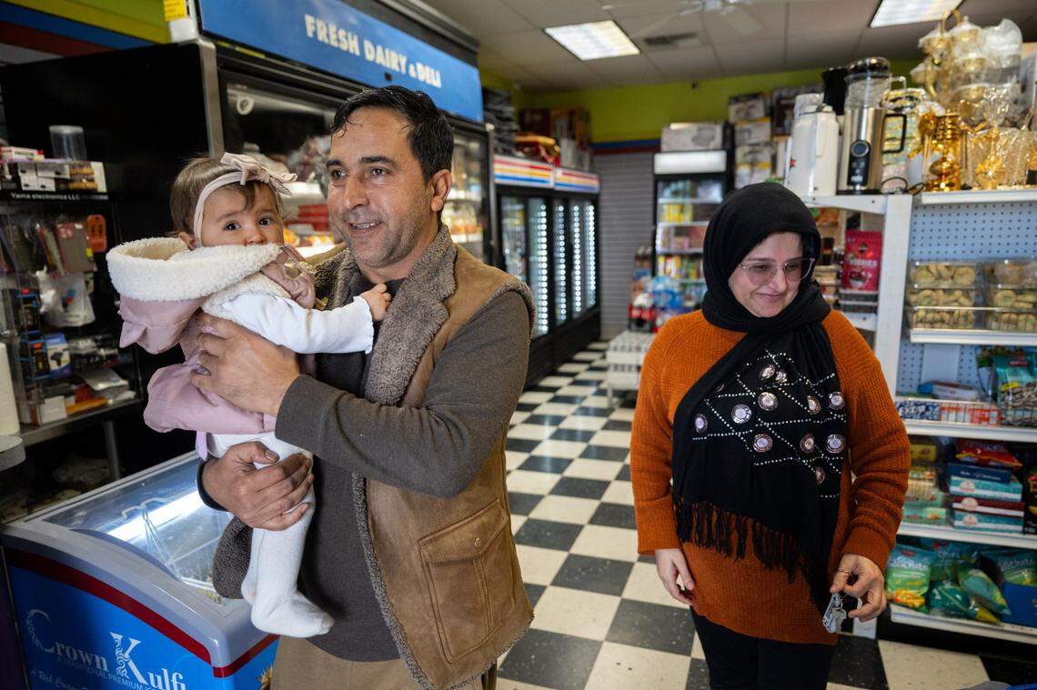 Store owner Mohammad Marouf Sharifi holds his daughter at Noble Halal Grocery in Yuba City last month. His Maleha, right, brought his lunch to the store. As a special immigrant visa holder, Sharifi went through a 3½ year vetting process to come to the U.S. in 2017.