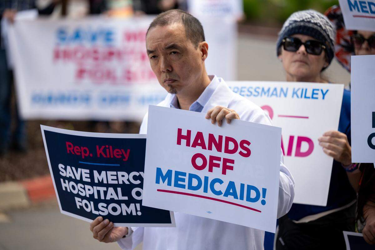 Dr. Ian Kim holds signs protesting potential cuts to Medicaid during a “Save Our Hospitals” rally at Folsom’s Dignity Health Mercy Hospital on Tuesday. According to organizers, the rally was one of more than 30 events planned statewide against a plan in Congress to cut $880 billion nationwide from the program, which is known as Medi-Cal in California.
