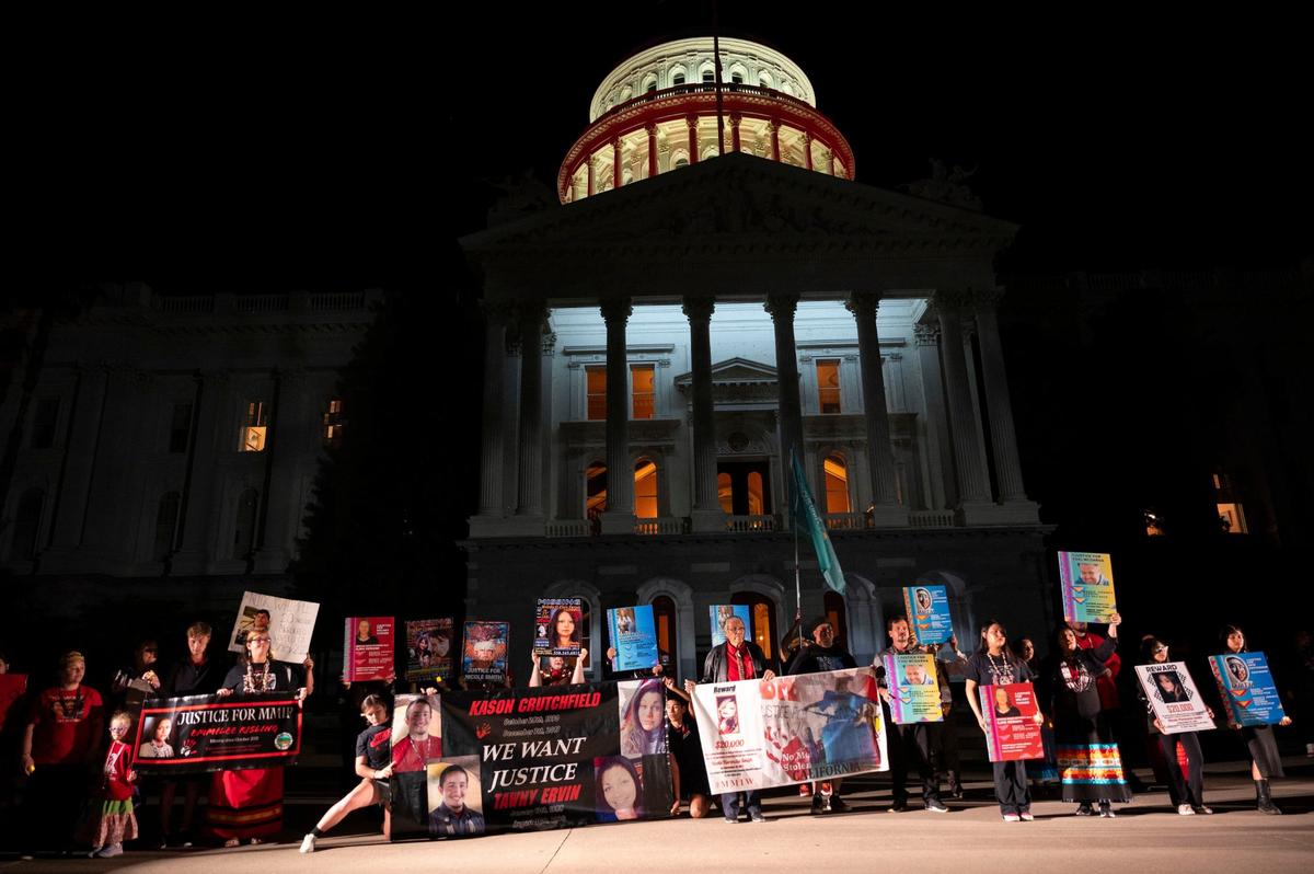 Family members hold signs of their lost loved ones on the west steps of the Capitol that was lit red to bring awareness during a Missing and Murdered Indigenous People candlelight vigil Wednesday, May 1, 2024.