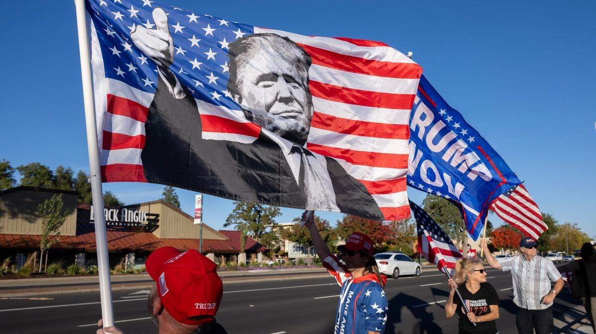 Trump supporters wave flags on Wednesday, Nov. 6, 2024, along Greenback Lane in Citrus Heights as they wait for the start of the Freedom Riders 1776 intrastate caravan celebrating his reelection.