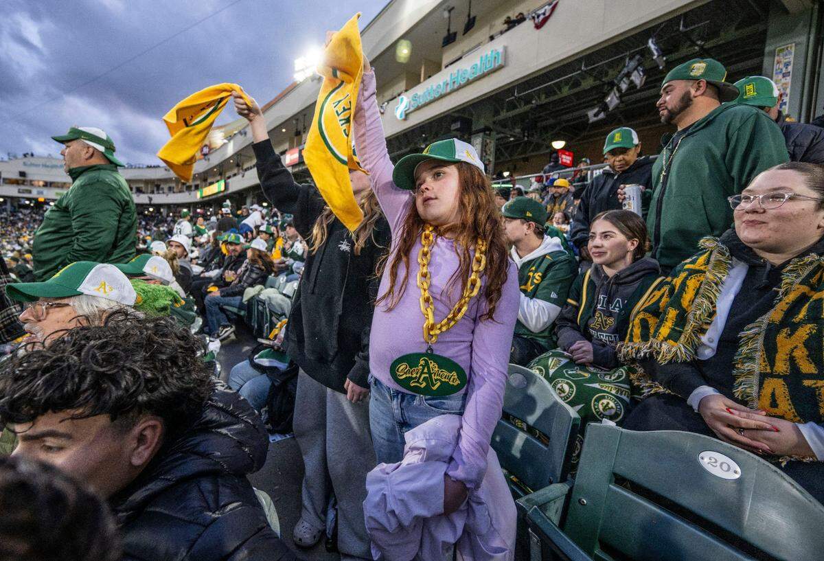 Lila Wood, 10, of Sacramento, waves a rally flag as she watches the first Athletics game in West Sacramento on Monday, March 31, 2025.