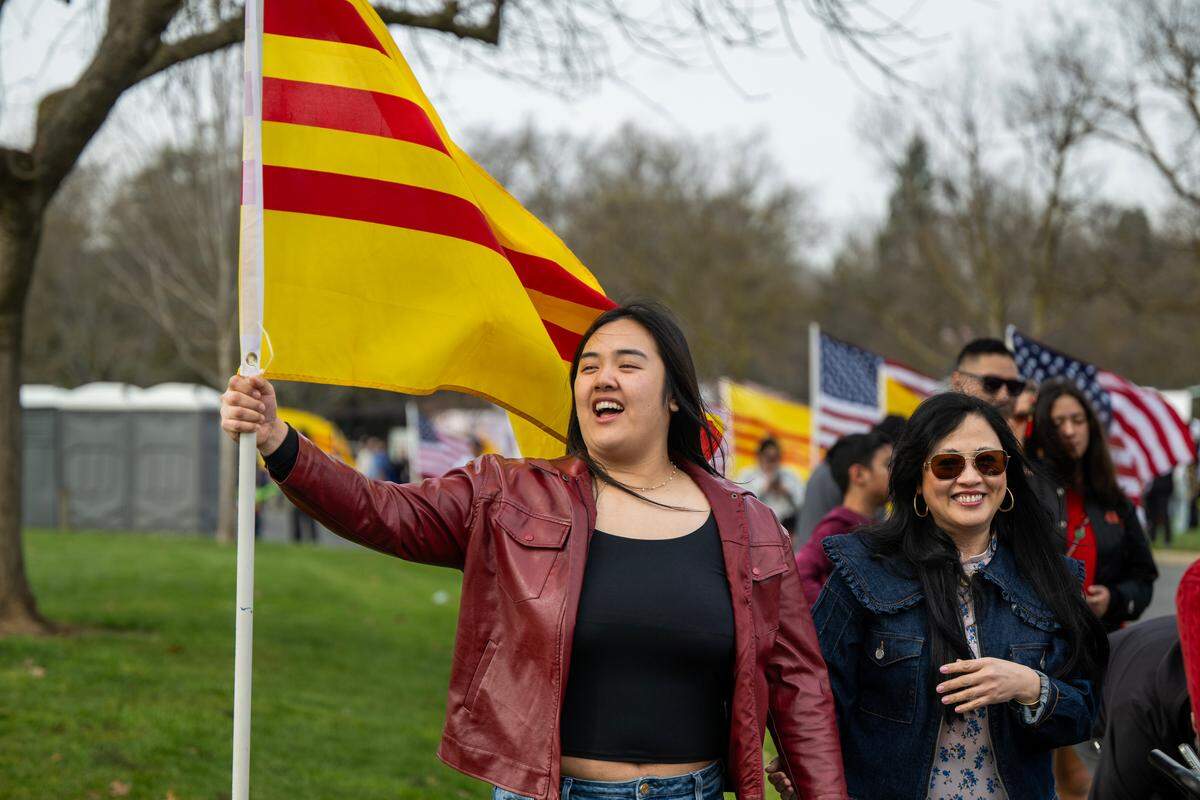Jackie Nguyen of San Francisco raises the Republic of Vietnam flag with her mother Judy Hinh at the Lunar New Year Tet festival at Elk Grove Park on Saturday.
