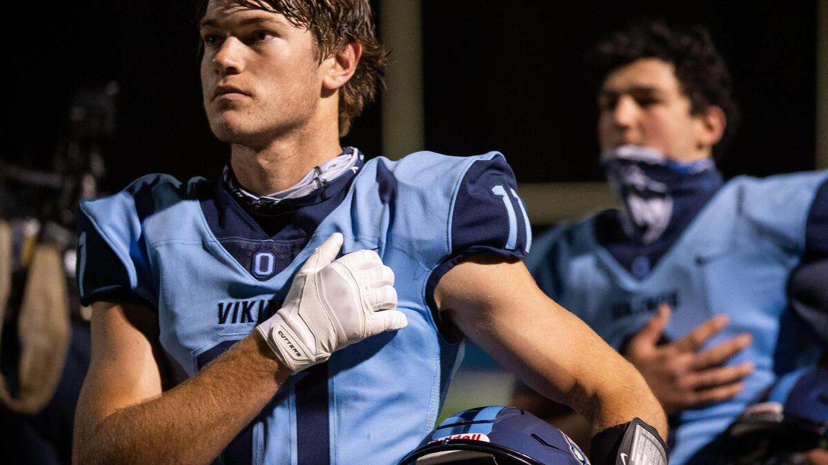 Oakmont High School’s James Mintmier and his teammates stand for the National Anthem before their football game against Ponderosa High School on Friday, March 12, 2021, at Oakmont in Roseville. Oakmont beat Ponderosa 15-7 for their opening game of the short spring season, adapted after year-long coronavirus pandemic school closures hampered high school athletics.