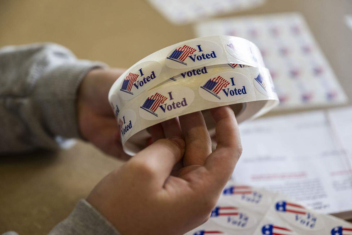 Carter Lavesque, a student election clerk, holds "I voted" stickers for Folsom residents at Folsom Lake College on Tuesday, Nov. 4, 2025.
