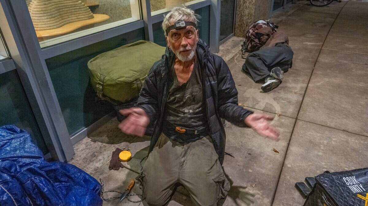 Randy Horn, 72, wears a camping light on his forehead as he prepares to sleep at Sacramento City Hall on July 15, 2025. On July 28 the city council voted to ban people from sleeping on or around city hall.