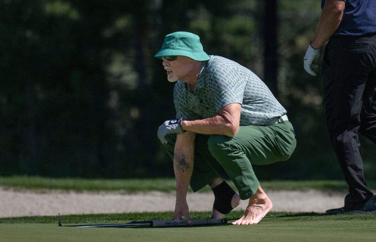 A barefoot Jim McMahon lines up his putter during the final day of the American Century Championship celebrity golf tournament at Edgewood Tahoe Resort in Stateline, Nev., on Sunday, July 13, 2025.