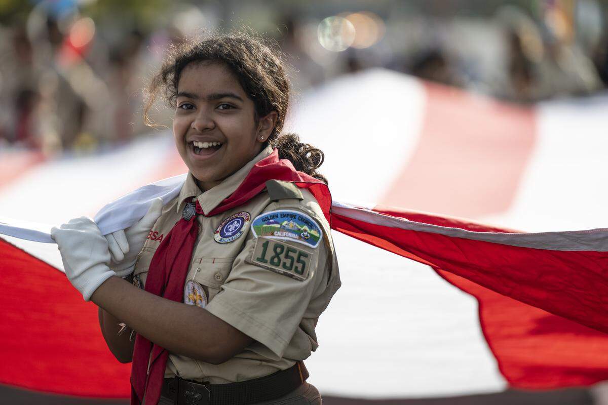Ariya Rath, a member of Boy Scout Troop 1855, helps her troop carry an American flag during a Veterans Day parade in Folsom on Tuesday, Nov. 11, 2025.