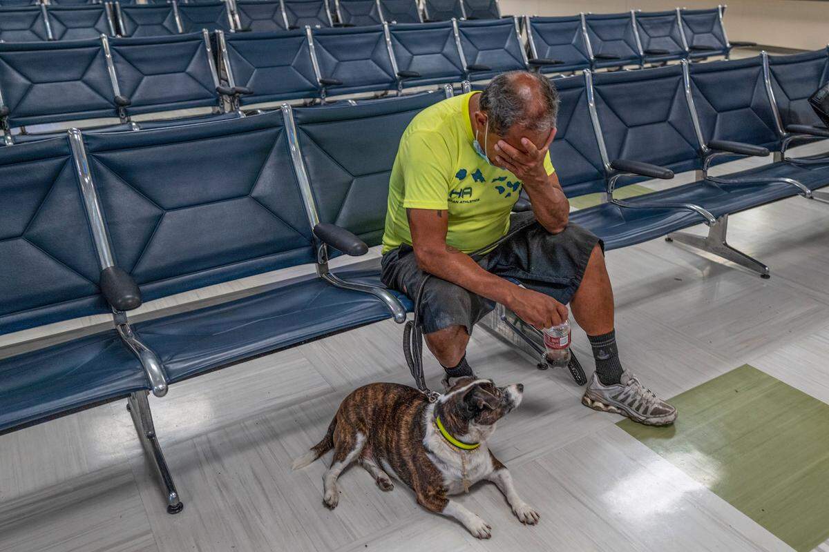 Antonio Macias, 61, sits in despair alongside his dog Ryder, 7, wearing a rosary, at a cooling center on Wednesday in Sacramento. His wife died recently of cancer and she used to care for the dog when he was working as a painter, he explained. After the death of his wife, he lost everything and sleeps outside City Hall.