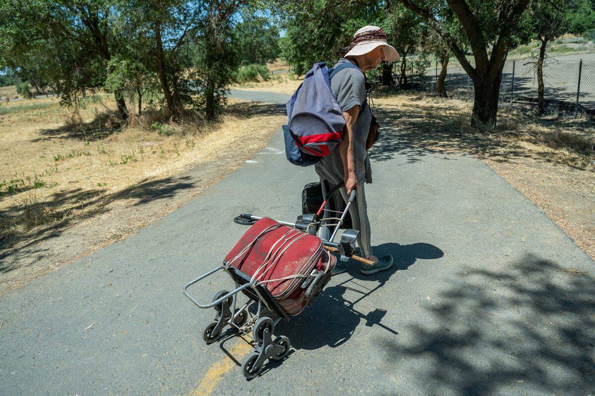 Carol Dutcher, 60, packs up belongings a friend dropped off at a park in Rio Linda on Friday, June 28, 2024. She had been swept from a homeless encampment last week and the friends had stored a few things in his car after her shelter was destroyed. She was going to bring them to a storage unit.
