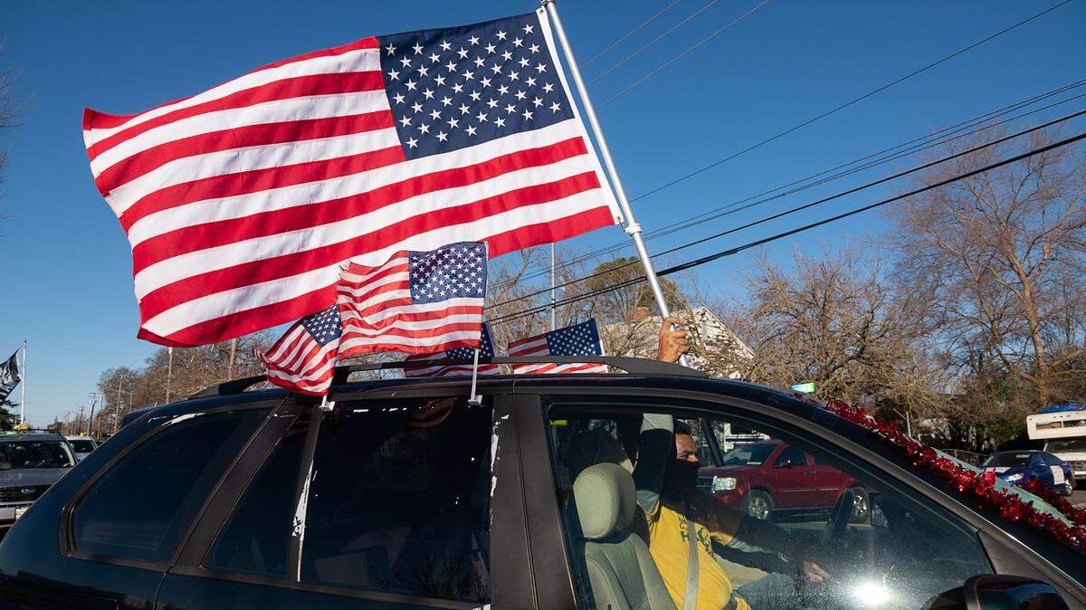 FILE - American flags fly on a car that joined the #ReclaimMLK Day car caravan in celebration of Martin Luther King Jr. Day on Jan. 18, 2021 in Sacramento.