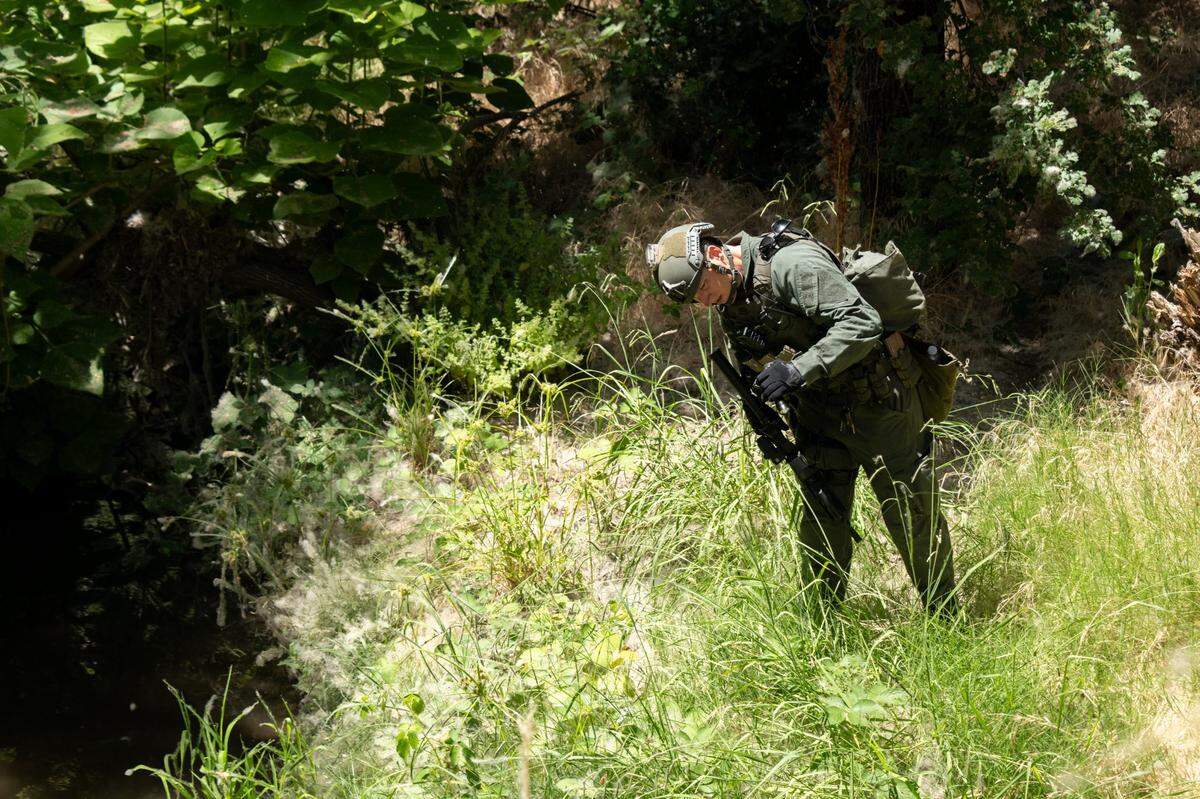 A police SWAT team member searches along Antelope Creek under Highway 65 for murder suspect Eric James Abril on Monday, July 10, 2023, a day after he escaped custody from a Roseville hospital.