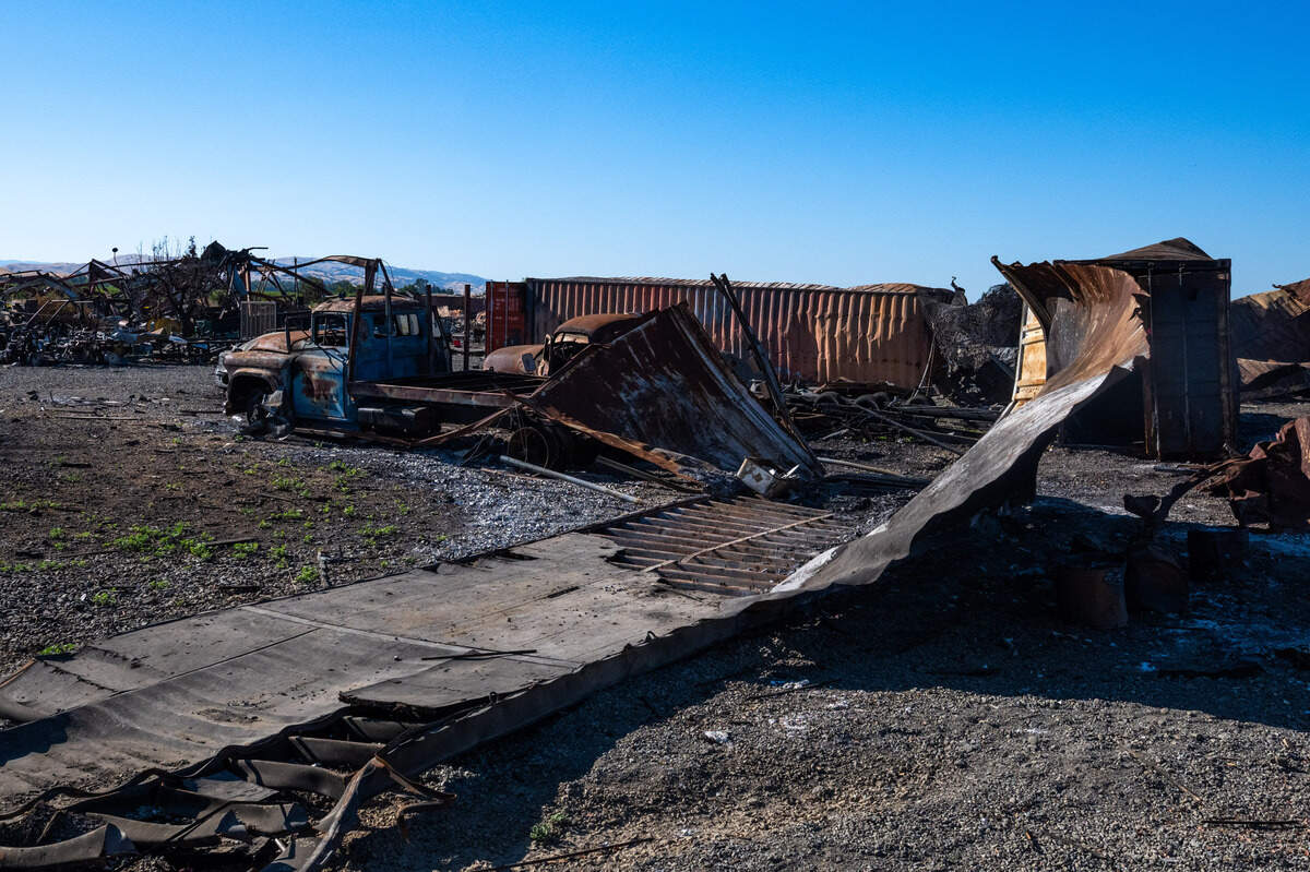 A peeled open shipping container rests near a burned truck at Esparto fireworks explosion site on Friday, July 18, 2025.