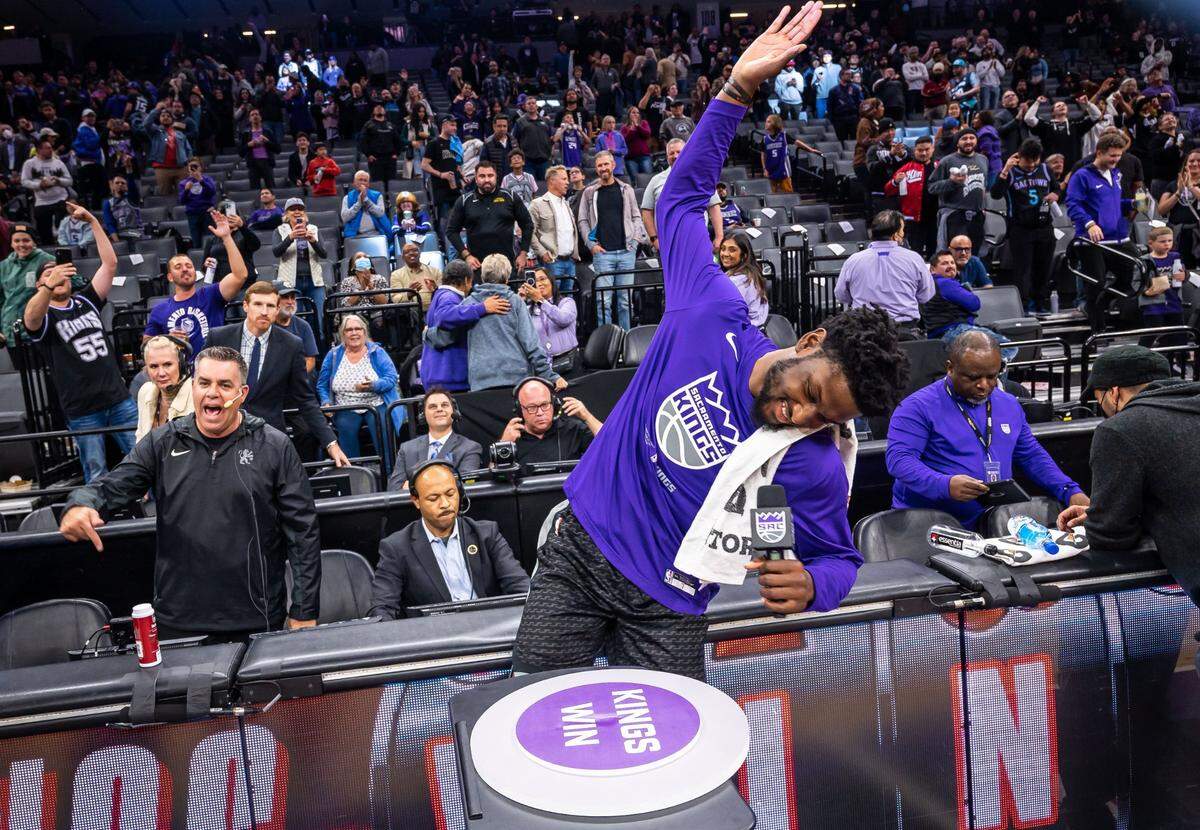 Sacramento Kings center Chimezie Metu (7) raises his hand to swing down on a “button” to light the beam after their 130-112 win over the San Antonio Spurs, as Kings public address announcer Scott Moak cheers at left, earlier this month.