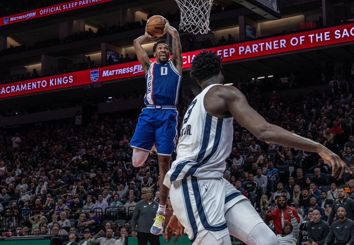 Sacramento Kings guard Malik Monk (0) dunks off a pass from teammate guard De’Aaron Fox (5) during an NBA game against the Memphis Grizzlies on Monday, March 18, 2024, at Golden 1 Center.
