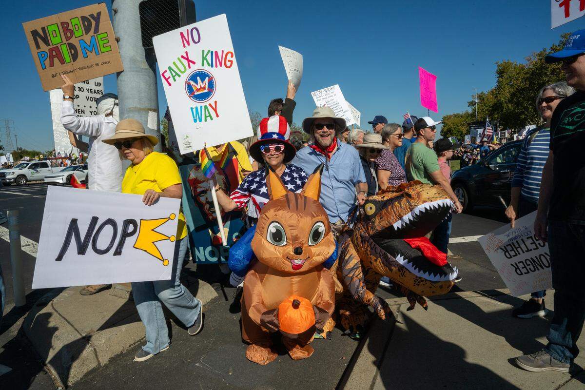 Pam O’Quin and Adam Quilici, center, dress as a squirrel and dinosaur as they participate in a "No Kings" rally on Saturday, Oct. 18, 2025, in Roseville.