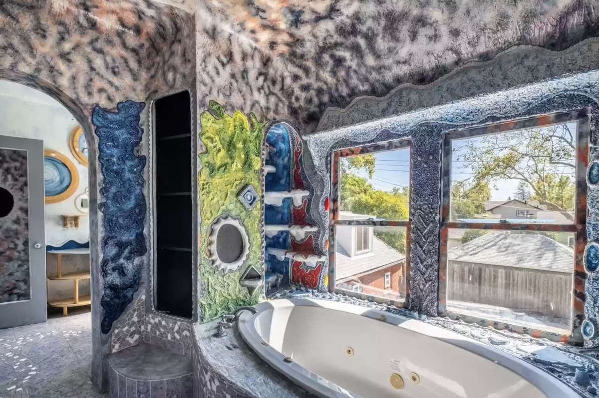 The home features four bedrooms and two bathrooms including this one with large windows framing the bathtub. The asking price for the home is $825,000.