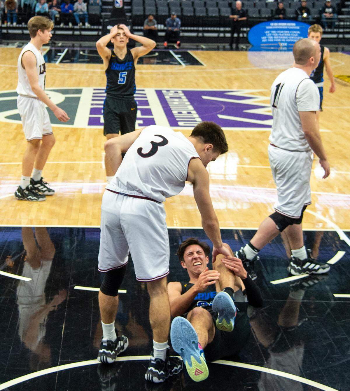 Valley Christian’s Russell Bugriyev ties to help injured Sacramento Waldorf player Elijah Neuhaus during the CIF Sac-Joaquin Section Division VI high school boys basketball championship game Friday.