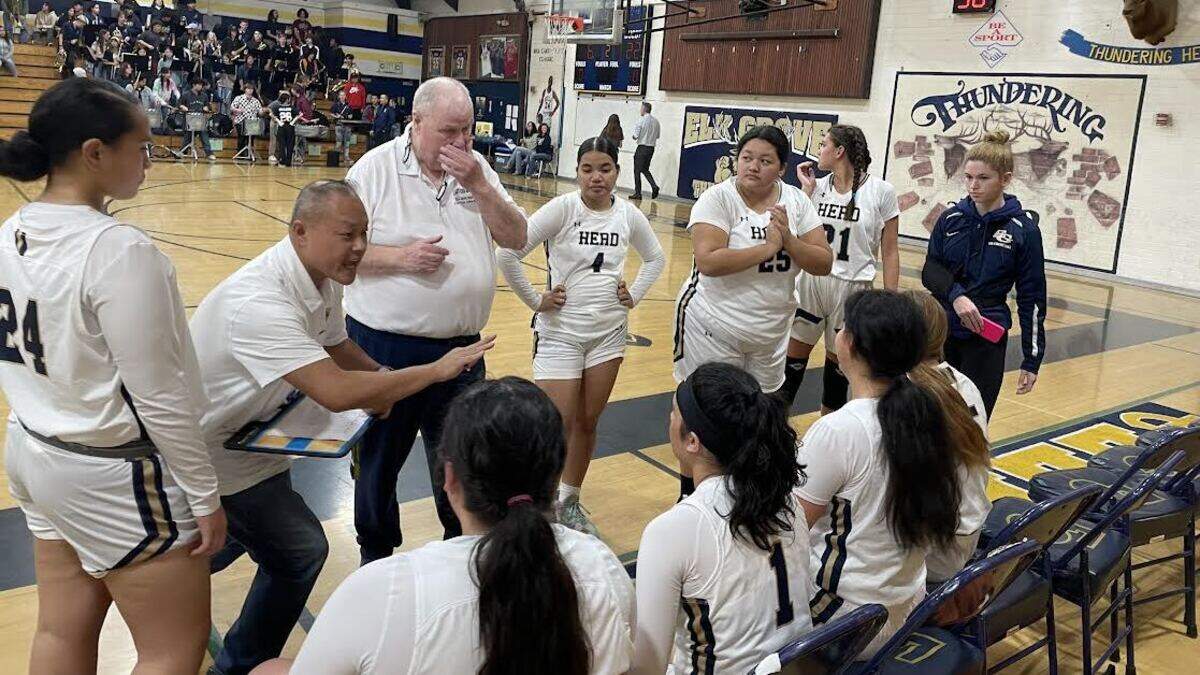 Elk Grove High School girls basketball coach Dave Crawford and assistant Peter Wong talk to their team during a timeout at Elk Grove’s Cartwright Gymnasium.