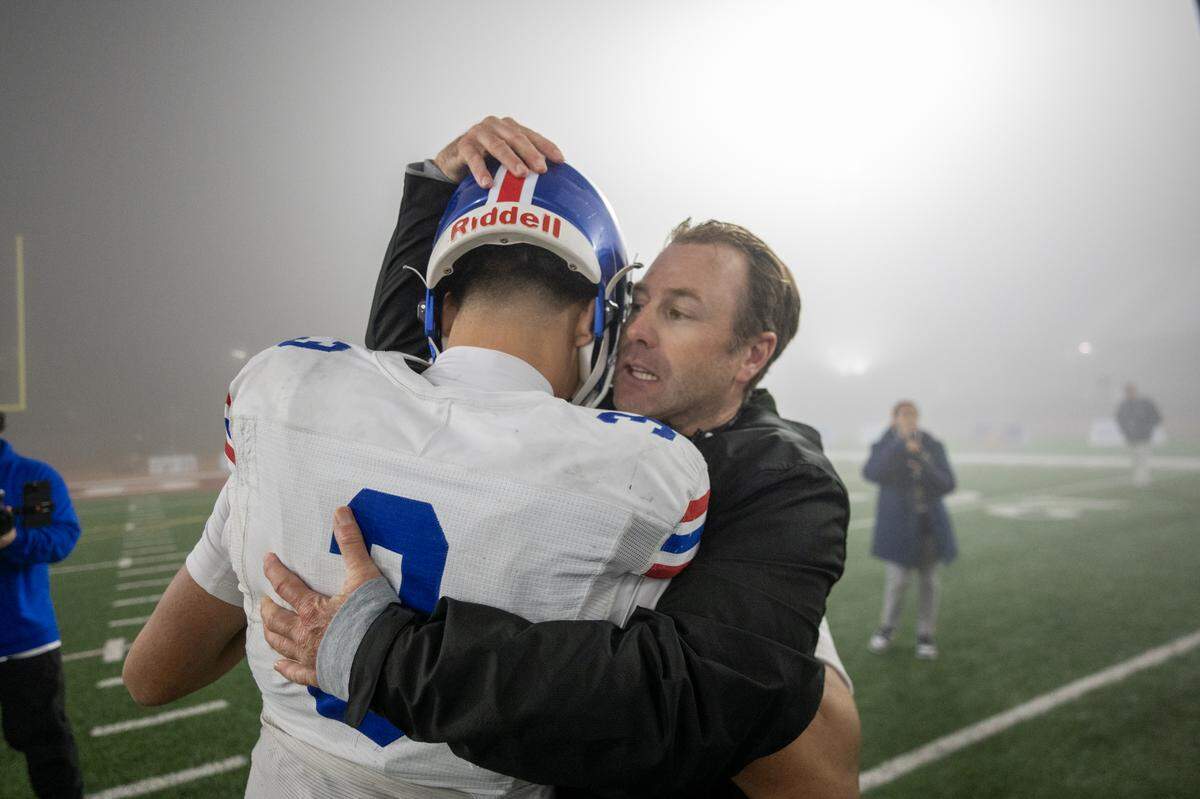 Folsom Bulldogs coach Paul Doherty embraces quarterback Ryder Lyons following the victory over the Cathedral Catholic Dons in the CIF Division 1-AA State Championship football game at Saddleback College in Mission Viejo on Friday.