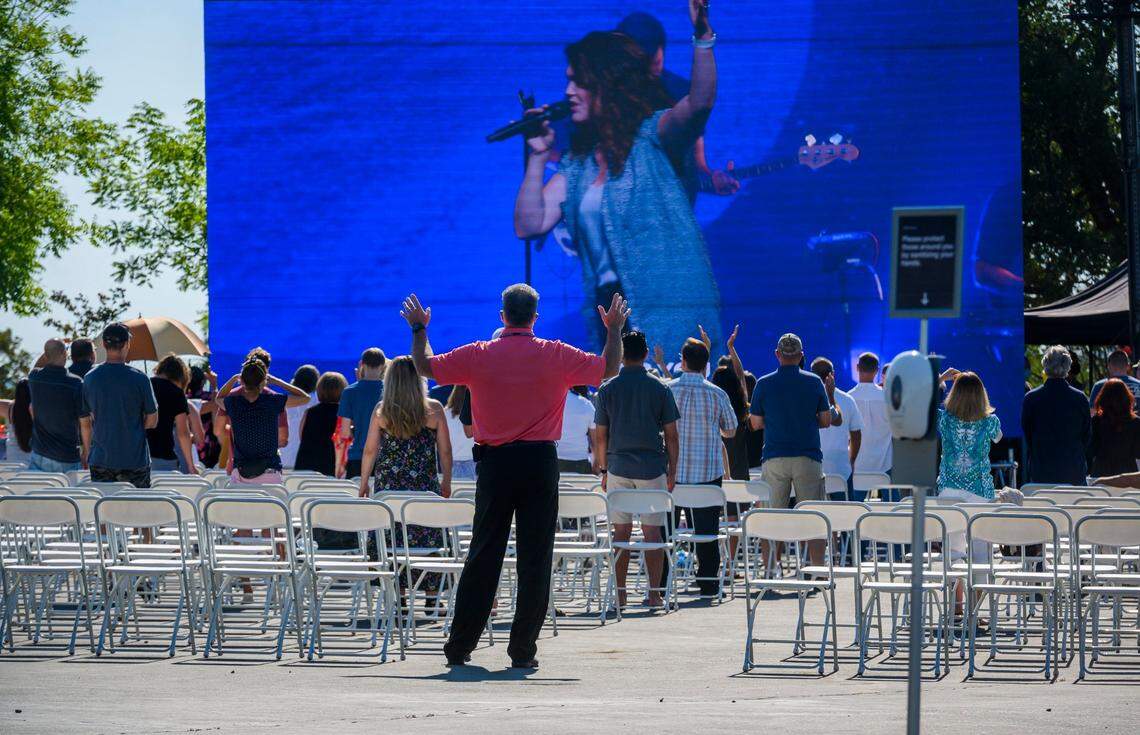 Members of Destiny Christian Church stand up at an outdoor seating area as an indoor service is held in July 2020. It was the church’s first day of Sunday services after Gov. Gavin Newsom ordered an end to indoor worship amid a resurgence of coronavirus cases.