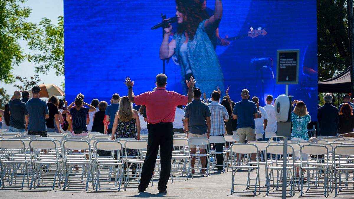 Members of Destiny Christian Church stand up at an outdoor seating area as an indoor service is held on Sunday, July 19, 2020 in Rocklin. It was the church’s first day of Sunday services since Gov. Gavin Newsom ordered an end to indoor worship amid a resurgence of coronavirus cases.