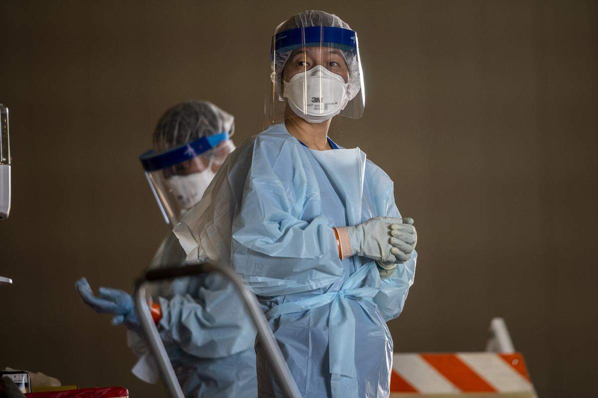 Nurses wearing PPE masks and two layers of gloves as they work in pairs inside the “hot zone” where they do testing for coronavirus at Cal Expo in Sacramento on Wednesday, April 15, 2020.