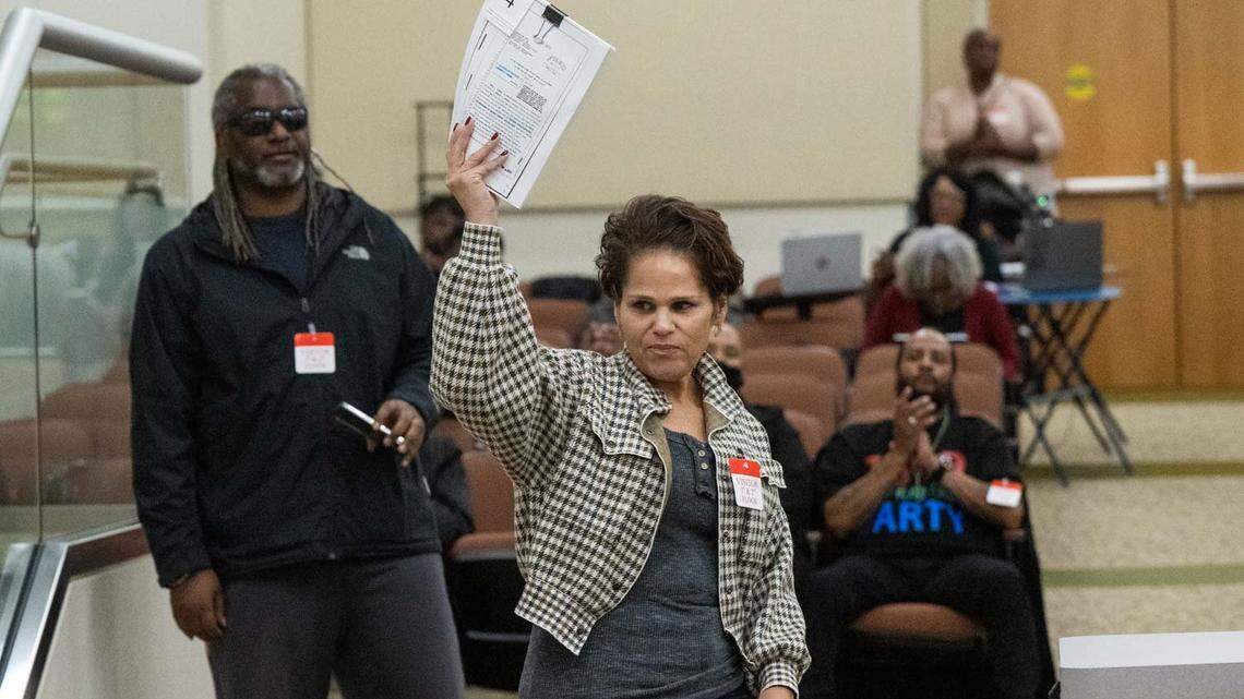 Dawn Basciano holds up legal documents while speaking during public comment at the California Reparations Task Force meeting on Wednesday, March 29, 2023, in Sacramento. She said her ancestors had land in Coloma taken by the state parks system.