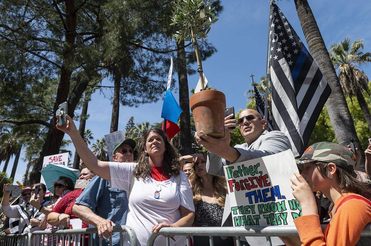Pastor Tim Thompson of Riverside holds an olive tree and offers it to the law enforcement officers during a protest at the state Capitol on Thursday, May 7, 2020 in Sacramento during the coronavirus pandemic.