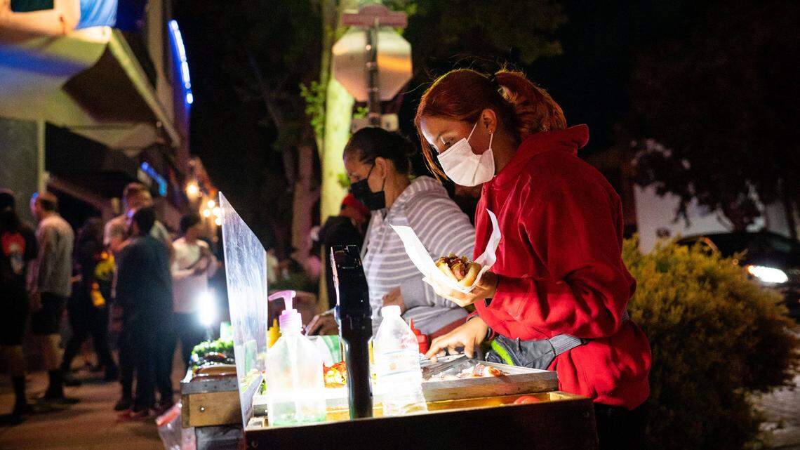 Genesis, one of several food vendors on J Street on Friday night, prepares hot dogs in the bustling Lavender Heights on June 11, 2021, in midtown Sacramento.