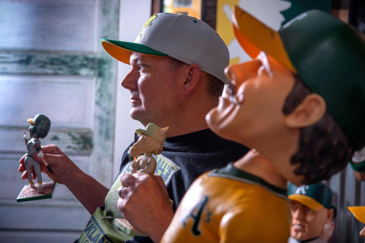 Robb Roberts holds bobbleheads of A’s legend Dave Henderson and his newest creation Charlie O – the mascot of the A’s when the team moved to Oakland – earlier this month at his office in Galt.