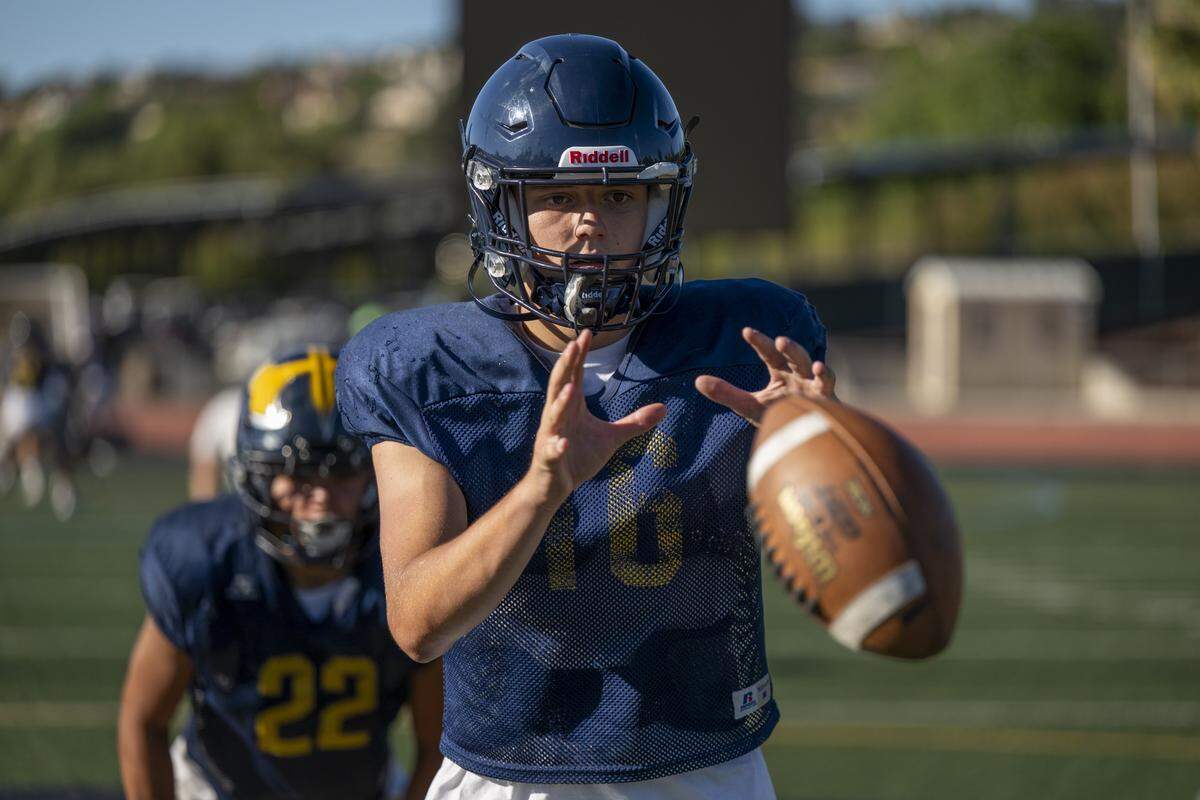A quarterback catches the ball thrown from his center before handing it off to his running back during a football practice at Oak Ridge High School in El Dorado Hills on Tuesday, Aug. 5, 2025.
