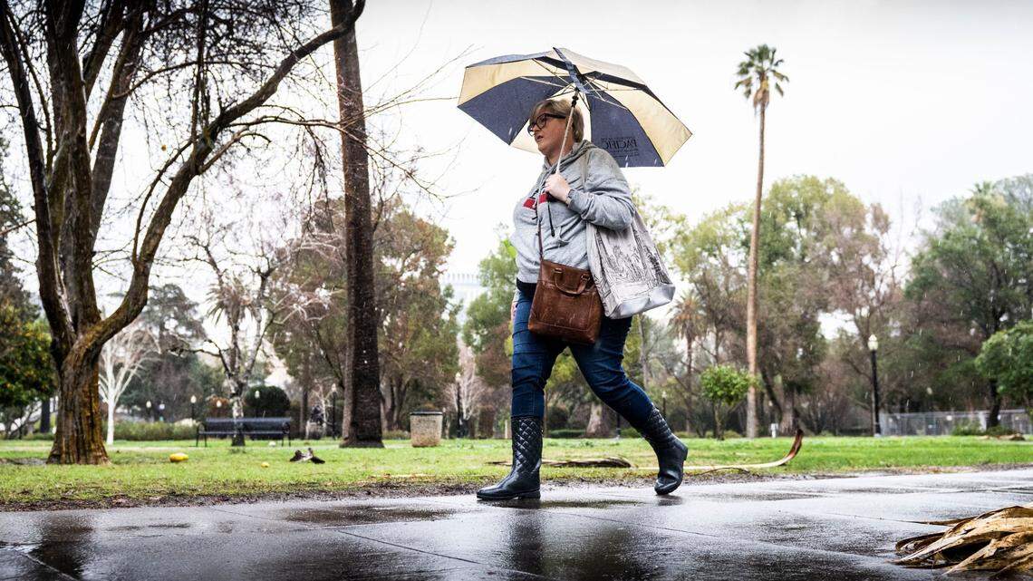 Andrea Clayton of Sacramento walks to her state job in the rain on N Street on Thursday, January 5, 2023.