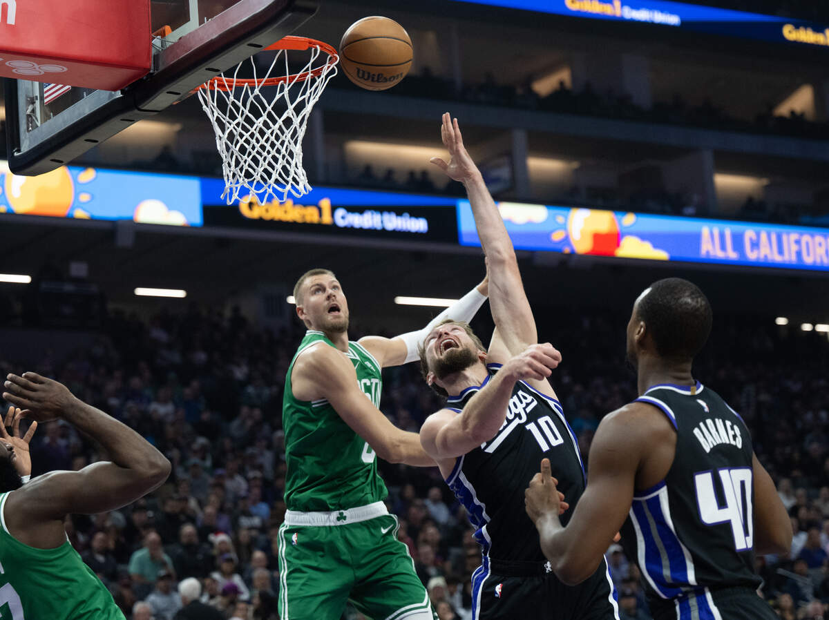 Sacramento Kings forward Domantas Sabonis (10) shoots a basket guarded by Boston Celtics center Kristaps Porzingis (8) during an NBA game at Golden 1 Center on Wednesday, Dec. 20, 2023.
