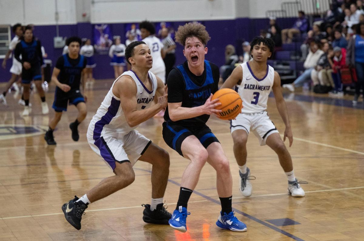 Capital Christian’s Jaylen Valdez, center, looks for an opening to shoot against the Sacramento Dragons in Oak Park in January.