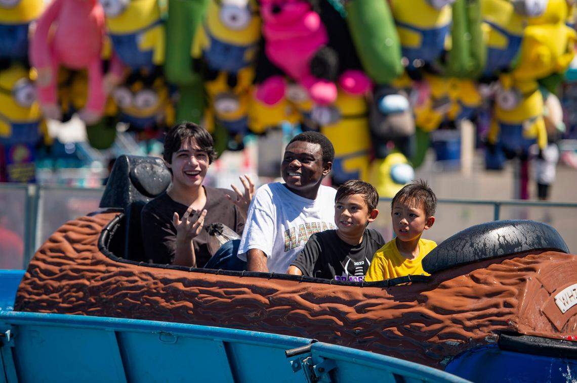 Curtis Wong, left; Nnaemeka Unanwa, second to left; Ezra Trinidad, 8, second to right; and Benjamin Chao, 8, right; react after getting splashed on the White Water ride at the California State Fair in 2022.