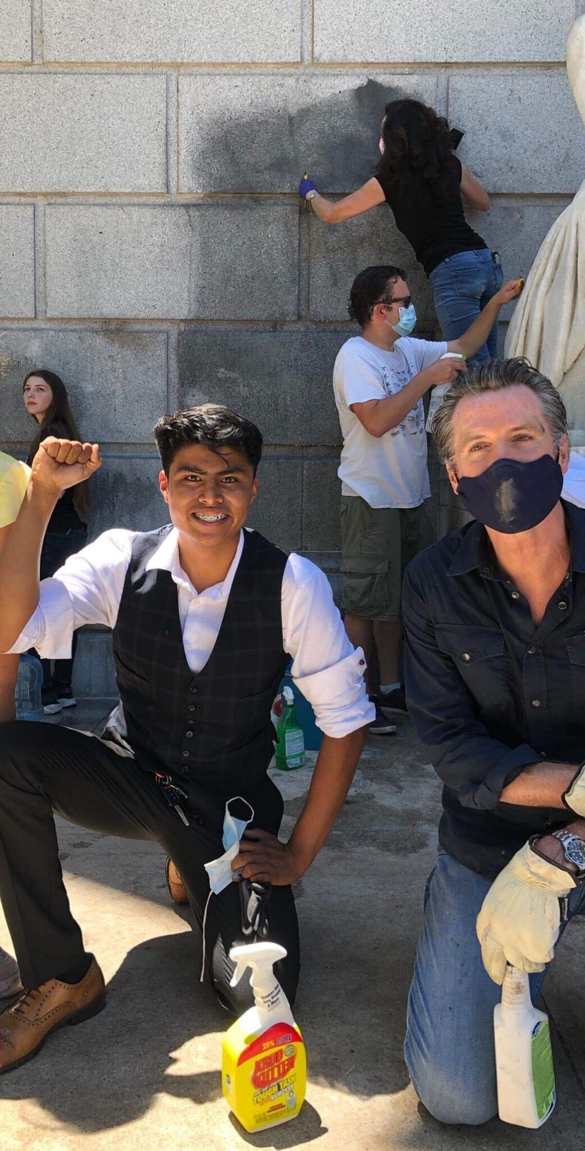 Victor Flores of San Jose, a recent high school graduate, poses with California Gov. Gavin Newsom as the two work on cleaning at the Stanley Mosk Courts Building west of the Capitol on Tuesday, June 2, 2020.