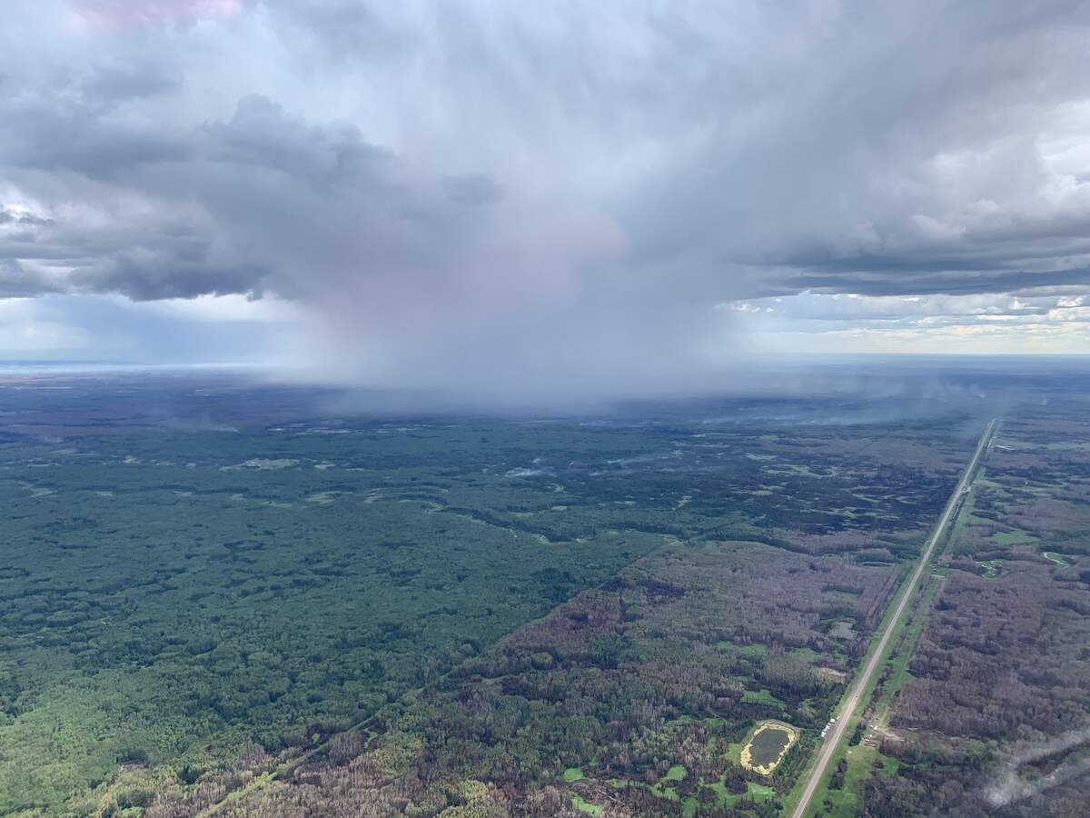 A thunderstorm above an Alberta forest generating wind that causes the wildfire to spread