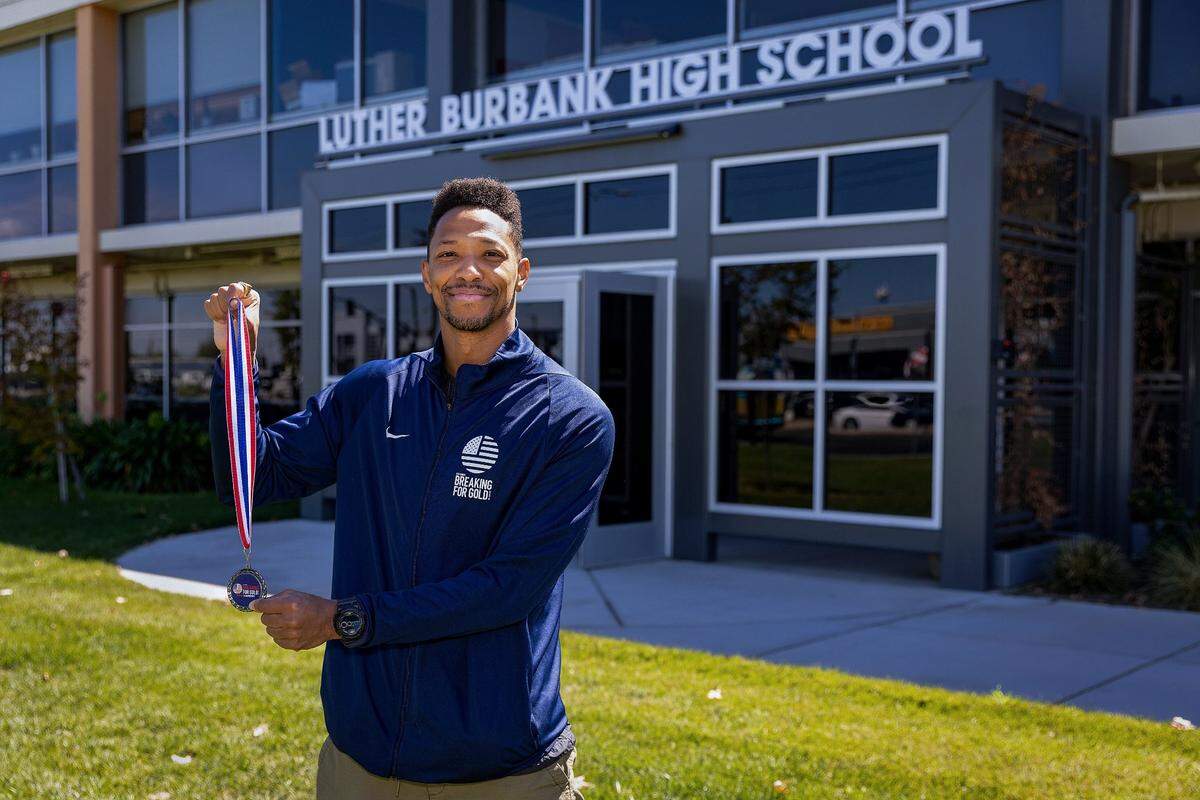 Breakdancer Morris Isby holds a Breaking for Gold medal last month in front of Burbank High School, where he discovered his love for breakdancing as a student. At 38, Isby has become one of the top U.S. breakdancers and hopes to compete in the 2024 Olympic games.