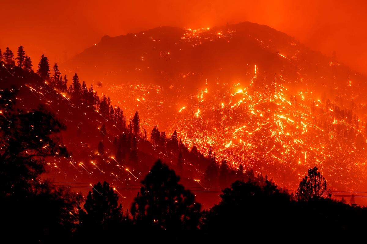 Seen in a long exposure photograph, embers light up hillsides as the Dixie Fire burns near Milford in Lassen County on Aug. 17, 2021.