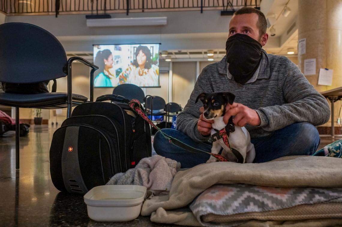 Homeless resident Anthony Munoz settles in for the night with his 15-week-old puppy, “Baby Girl,” at the warming center at Tsakopoulos Library Galleria on Wednesday, Jan. 27, 2021, in downtown Sacramento. Munoz said they stayed outside City Hall on Tuesday night during the most severe winter storm of the season.