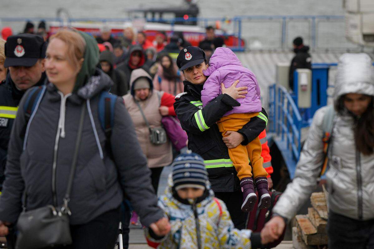 A firefighter holds the child of a refugee fleeing the war from neighboring Ukraine as they wait to be processed by border police after crossing the border by ferry at the Isaccea-Orlivka border crossing, in Romania on Friday.