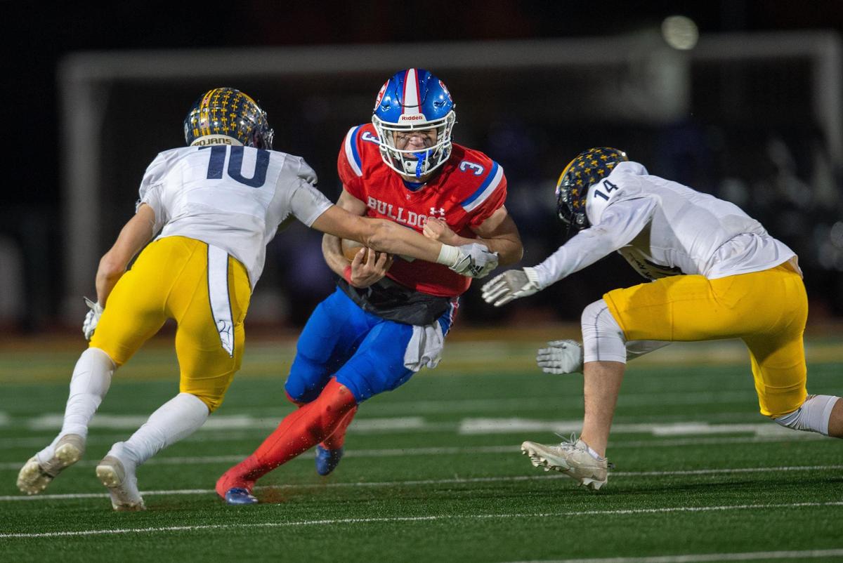 Folsom Bulldogs quarterback Ryder Lyons (3) prepares to be tackled by Oak Ridge Trojans defenders Jasen Womack (10) and Bo Gordon (14) in the second half of the CIF Sac-Joaquin Section Division I football championship game on Friday, Nov. 24, 2023, at Hughes Stadium.