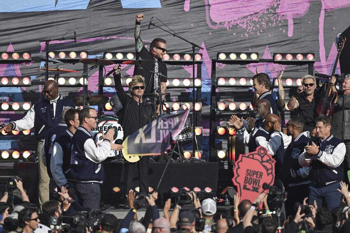 NFL Hall of Famers, including quarterbacks Peyton Manning at left and Steve Young at right, applaud the end of Green Day's opening act performance before the start of Super Bowl LX at Levi’s Stadium in Santa Clara on Sunday, Feb. 8.