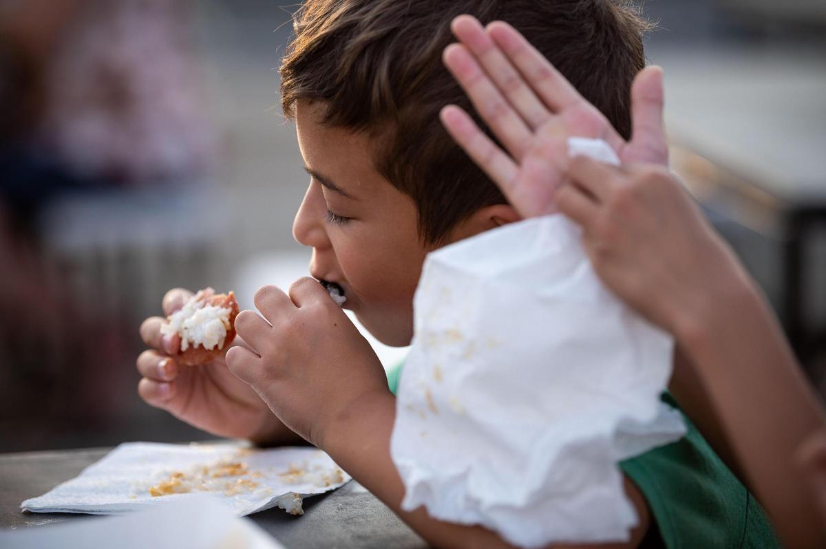 Dominic Pudwill, 7, of Roseville, eats Spam musubi alongside family and friends at FoodieLand at Sacramento’s Cal Expo on Saturday, Sept. 4, 2021.
