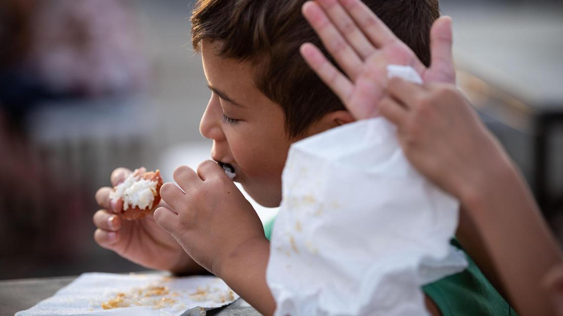 Dominic Pudwill, 7, of Roseville, eats Spam musubi alongside family and friends at FoodieLand Night Market for an Asian inspired pop-up festival at Sacramento’s Cal Expo on Saturday, Sept. 4, 2021, which featured food trucks, local art, drinks and entertainment.