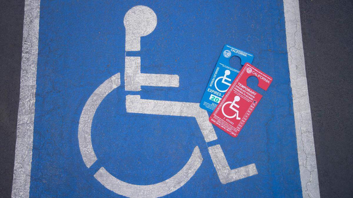 Disabled person parking placards placed beside a disabled parking space. Senate Bill 611 changed the renewal process for permanent disabled placards.